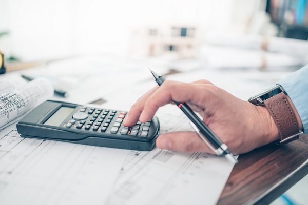 Architect engineer use calculator for calculate drawing design w Architect engineer use calculator for calculate drawing design working on bueprint. House planning design and construction concept.